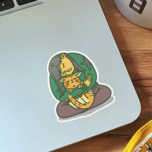 Vinyl sticker on laptop of a a girl, rubbing her face on the head of an orange cat 