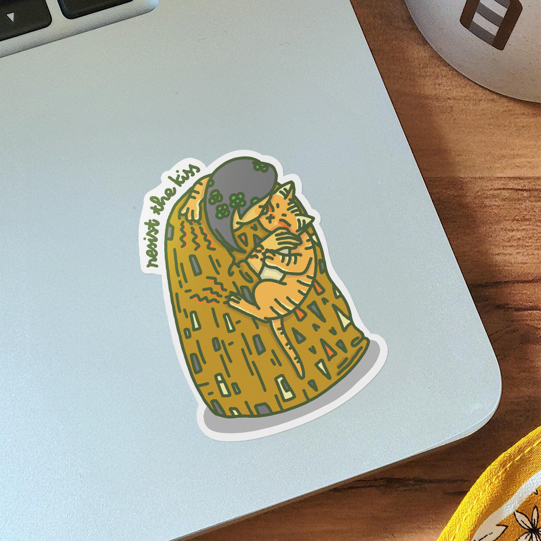 Vinyl sticker on laptop of a Gustav Klimt The Kiss but with a girl trying to kiss an orange cat, and the cat is resisting the kiss