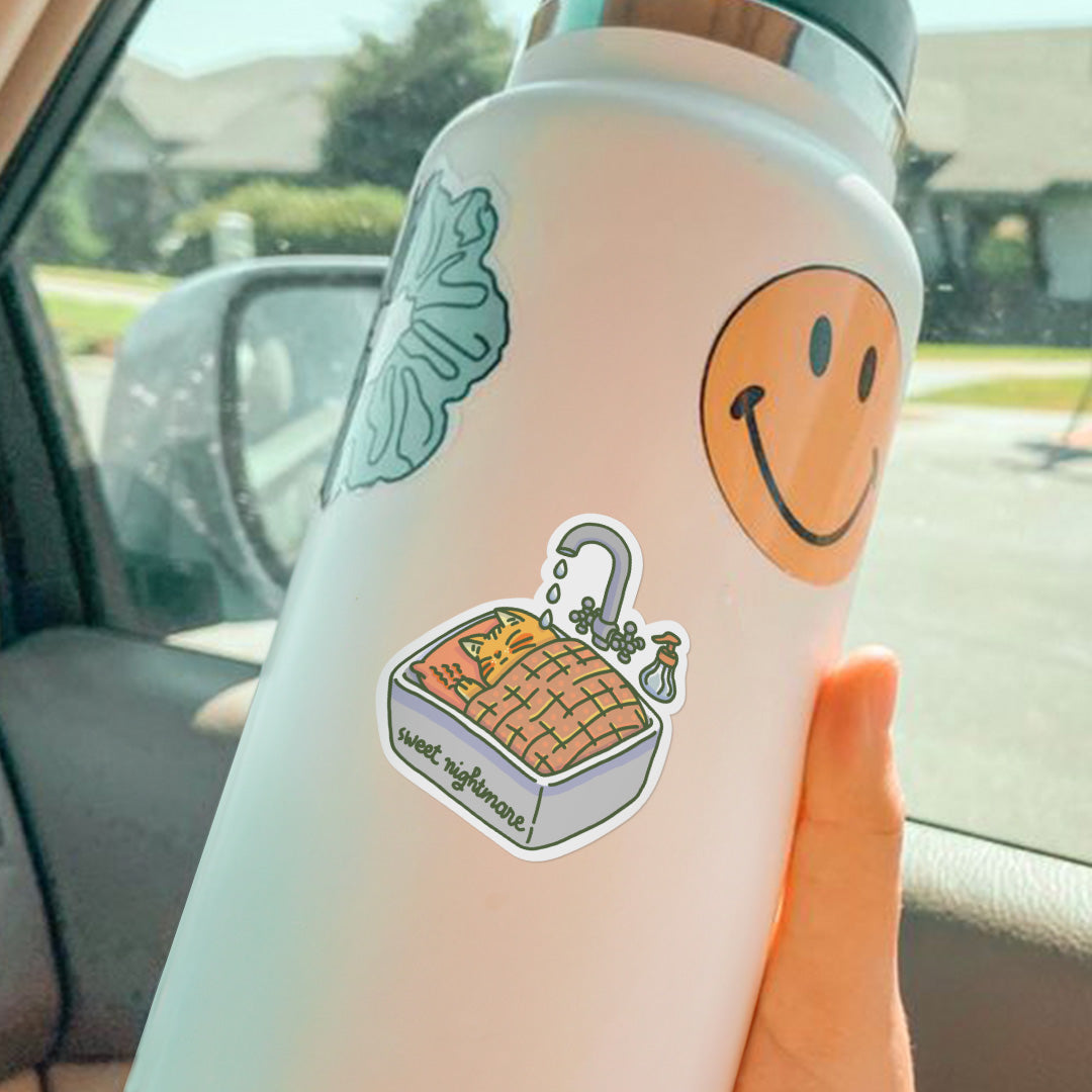 Vinyl sticker on water bottle of a cute orange cat sleeping in the sink, but some water drops from the faucet is disturbing him.