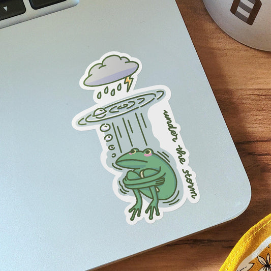 Vinyl sticker on laptop of a cute green frog hiding from the storm, rain and thunder underneath water